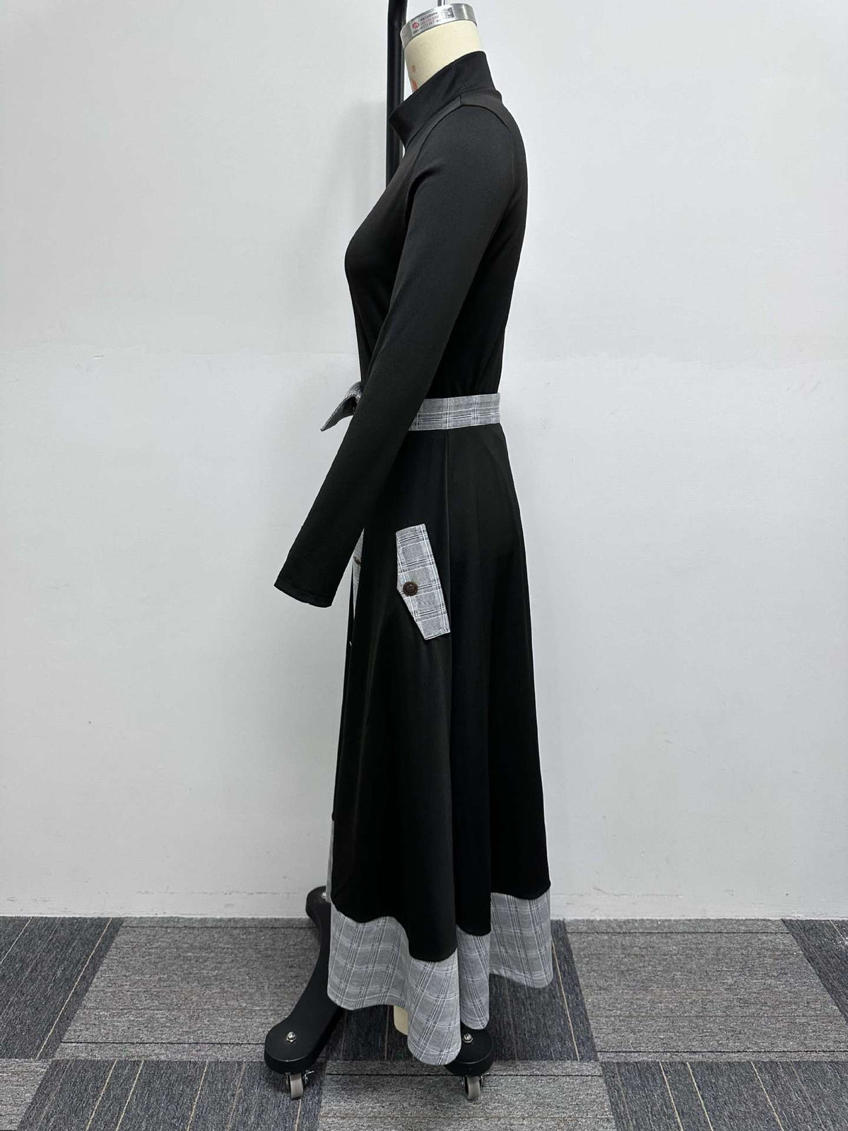 Side view of the black and grey plaid skirt set on a mannequin, showing the waist tie and plaid pocket detail.
